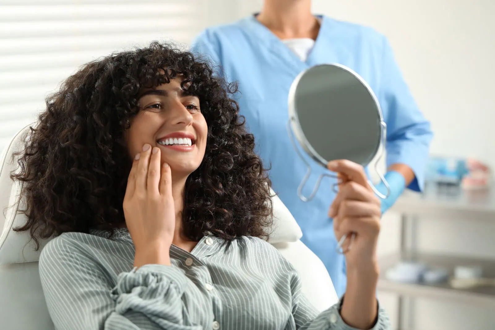 Patient admiring her smile in a hand mirror after a checkup